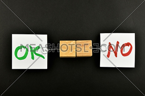Approval ok and no, two white paper notes with wooden holders in different directions isolated on black paper background for presentation