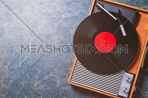Older Gramophone with a vinyl record on wooden table, top view and copy space,photo.