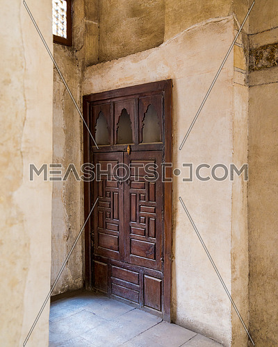 Angle view of wooden aged door on grunge stone wall, Medieval Cairo, Egypt