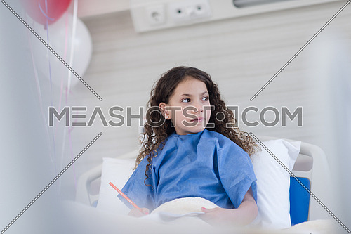 little middle eastern girl painting home and family at hospital bed in a large modern hospital