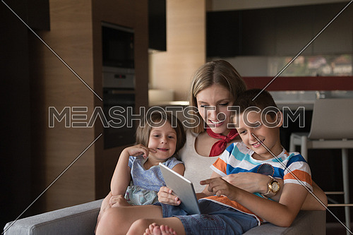 happy Mother spending time with kids using tablet computer on an armchair  at home