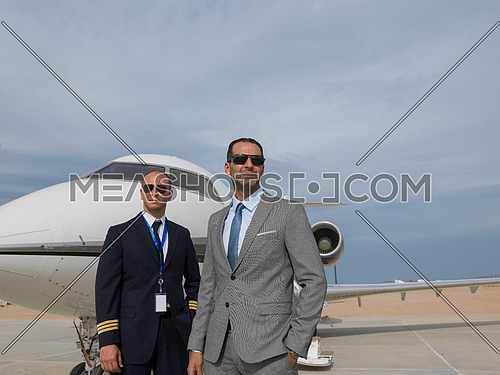 portrait of middle eastern pilot and a successful businessman in front of private airplane