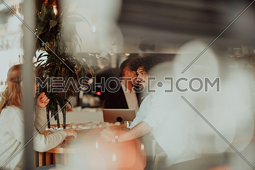 a woman in glasses and men with afro hair sit in a cafe and talk about business projects