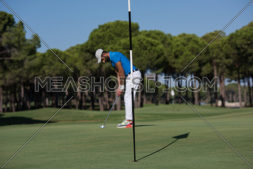 golf player hitting shot with driver on course at beautiful sunny day