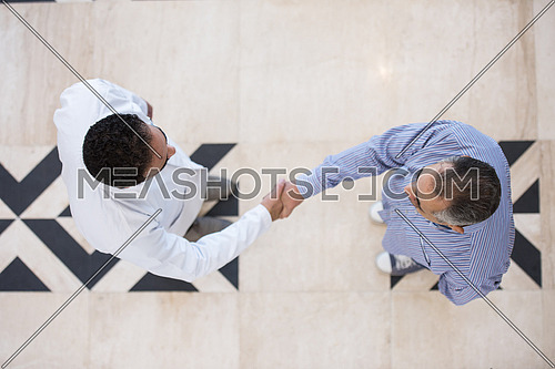 top view of smiling middle eastern doctor at the clinic giving an handshake to his patient, healthcare and professionalism concept