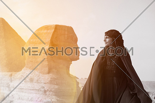 egyptian woman in traditional bedouin clothes in front of ancient great giza pyramids  and sphinx profile