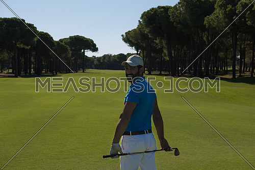 handsome middle eastern golf player portrait from back with course in background  at beautiful sunny day
