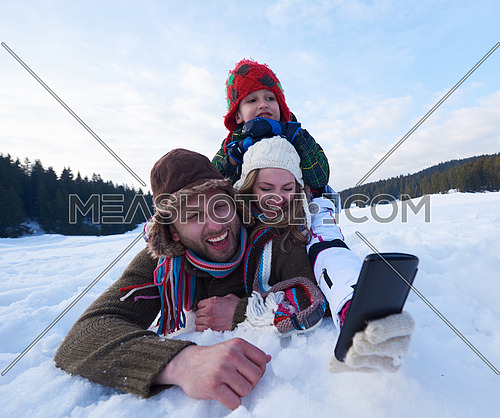 happy  romantic couple have fun in fresh snow and taking selfie. Romantic winter scene in forest with young people