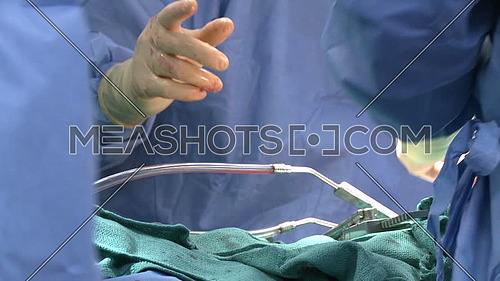 Long shot for doctor hand from behind while performing surgery