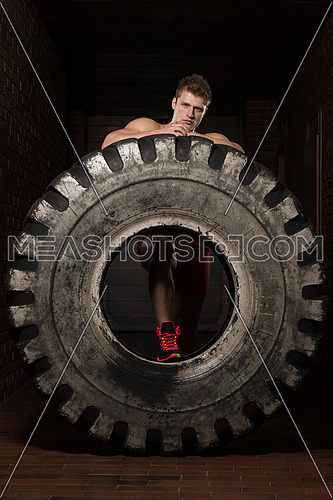 Young Muscular Man with Truck Tire Resting Afther Doing Crossfit Style Workout Turning Tire Over