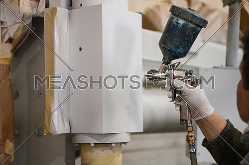A worker painting to mechanical part with airless spray. High quality photo