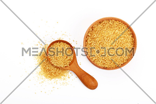 Wooden scoop spoon and bowl full of brown cane sugar with pinch of sugar spilled around isolated on white background, top view