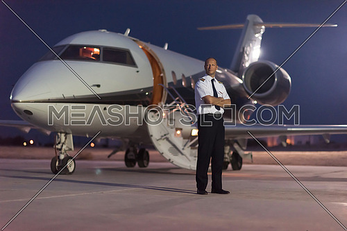 Portrait of a young middle eastern successful pilot in front of private jet one summer evening