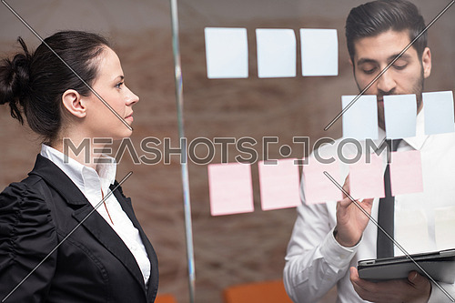 young creative startup business people on meeting at modern office making plans and projects with post stickers on glass