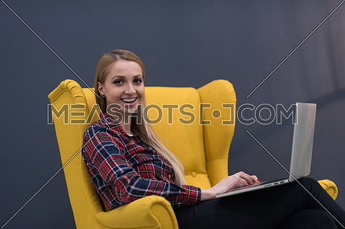 startup business, woman  working on laptop computer at modern office and sitting on creative yellow armchair