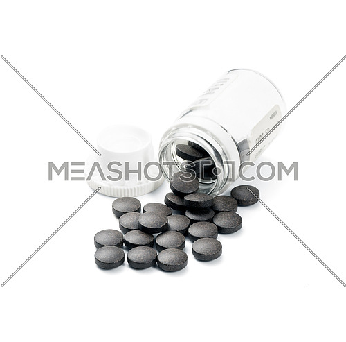 brown pills spilled from glass bottle on white background