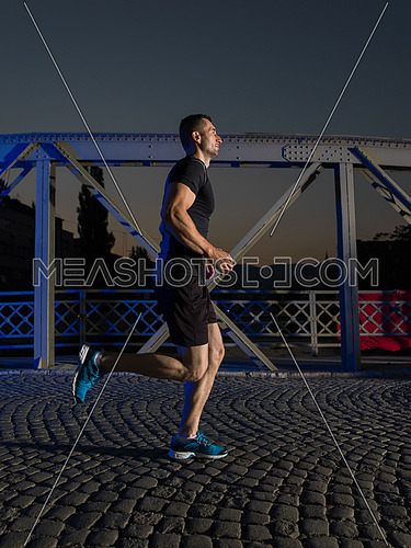 urban sports, young healthy man jogging across the bridge in the city at early morning in night