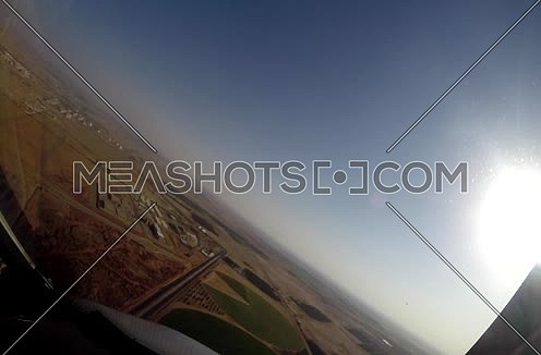 Close shot from inside plane cockpit showing sky horizon from the window and a city at day