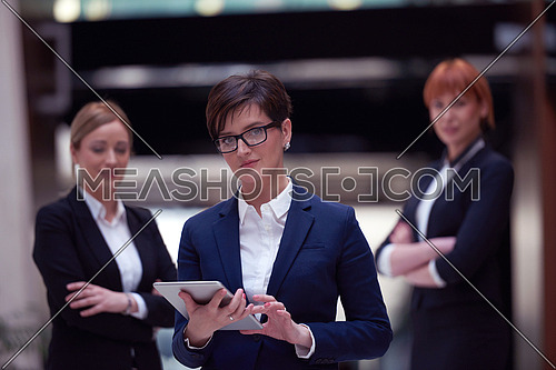 young business woman group,  team standing in modern bright office and working on tablet computer