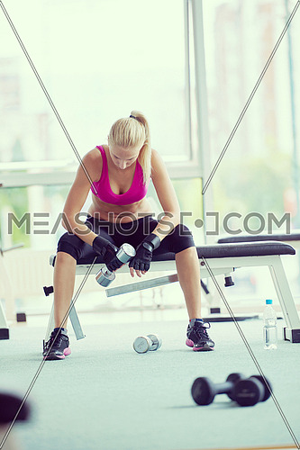 halethy young woman exercise with dumbells and relaxing on banch in fitness gym