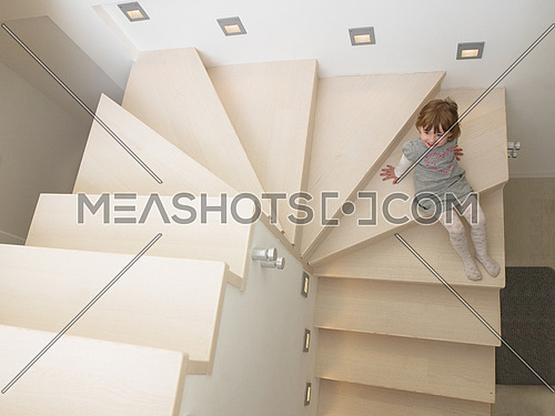 little cute girl enjoying on the stairs in a modern living room of her luxury home
