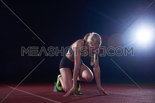 woman  sprinter leaving starting blocks on the athletic  track. Side view. exploding start