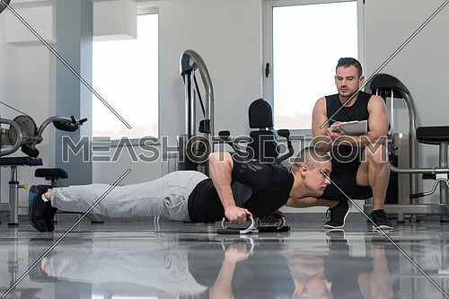 Personal Trainer Showing Young Man How To xercise Push-Up Strength In A Health And Fitness Concept