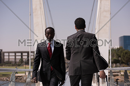 african businessman walking across modern footbridge