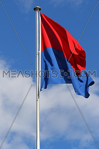 Flag of the State and Republic of Canton Ticino, Switzerland, flapping in the wind against blue skies and white clouds