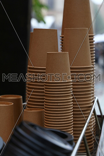 Close up stack of brown disposable kraft paper cups on coffee machine, low angle view