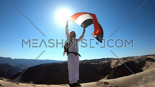Follow shot for bedouin man holding Egyptian Flag in Sinai Trail from Ain Hodouda at day. 