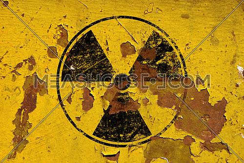 Black radioactive hazard warning sign painted over grunge yellow metal wall background with copy space