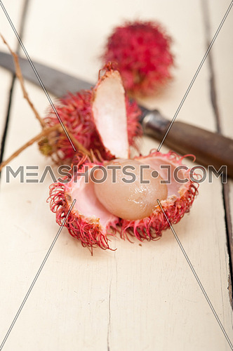 fresh tropical rambutan fruits over rustic wood table 